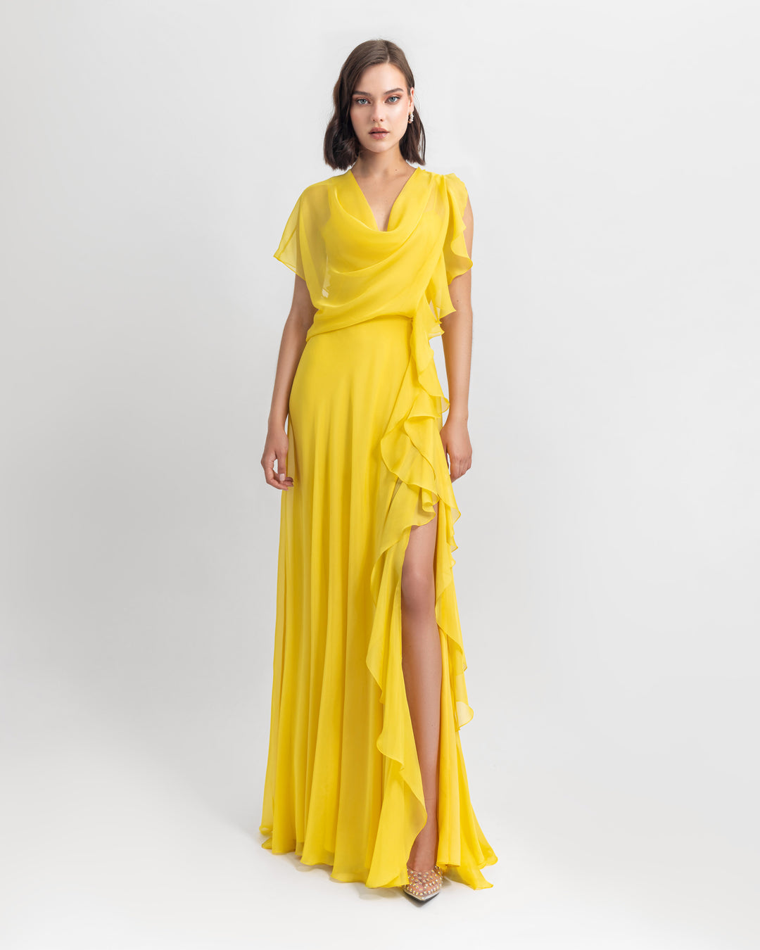 An asymmetrical flared chiffon yellow dress with draping and ruffled details.