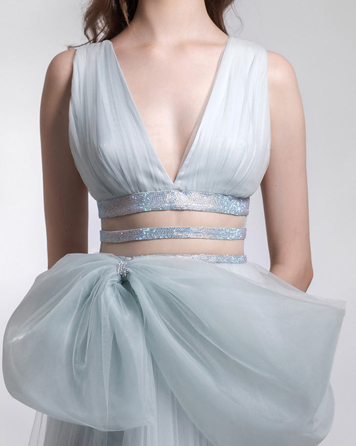 A close-up of a deep V-neckline tulle dress with cut outs and an asymmetrical bow-like detail on the waist.