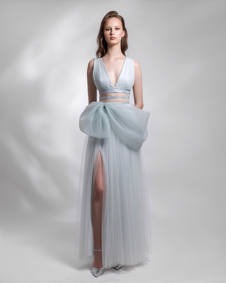 A deep V-neckline tulle dress with cut outs, an asymmetrical bow-like detail on the waist, and a slit on the side.