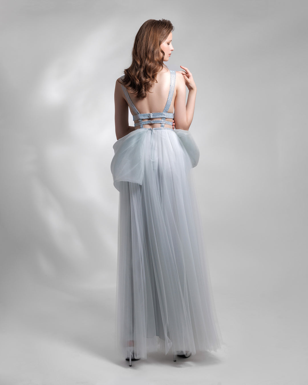 An open back tulle evening dress with cut outs and an asymmetrical bow-like detail on the waist.