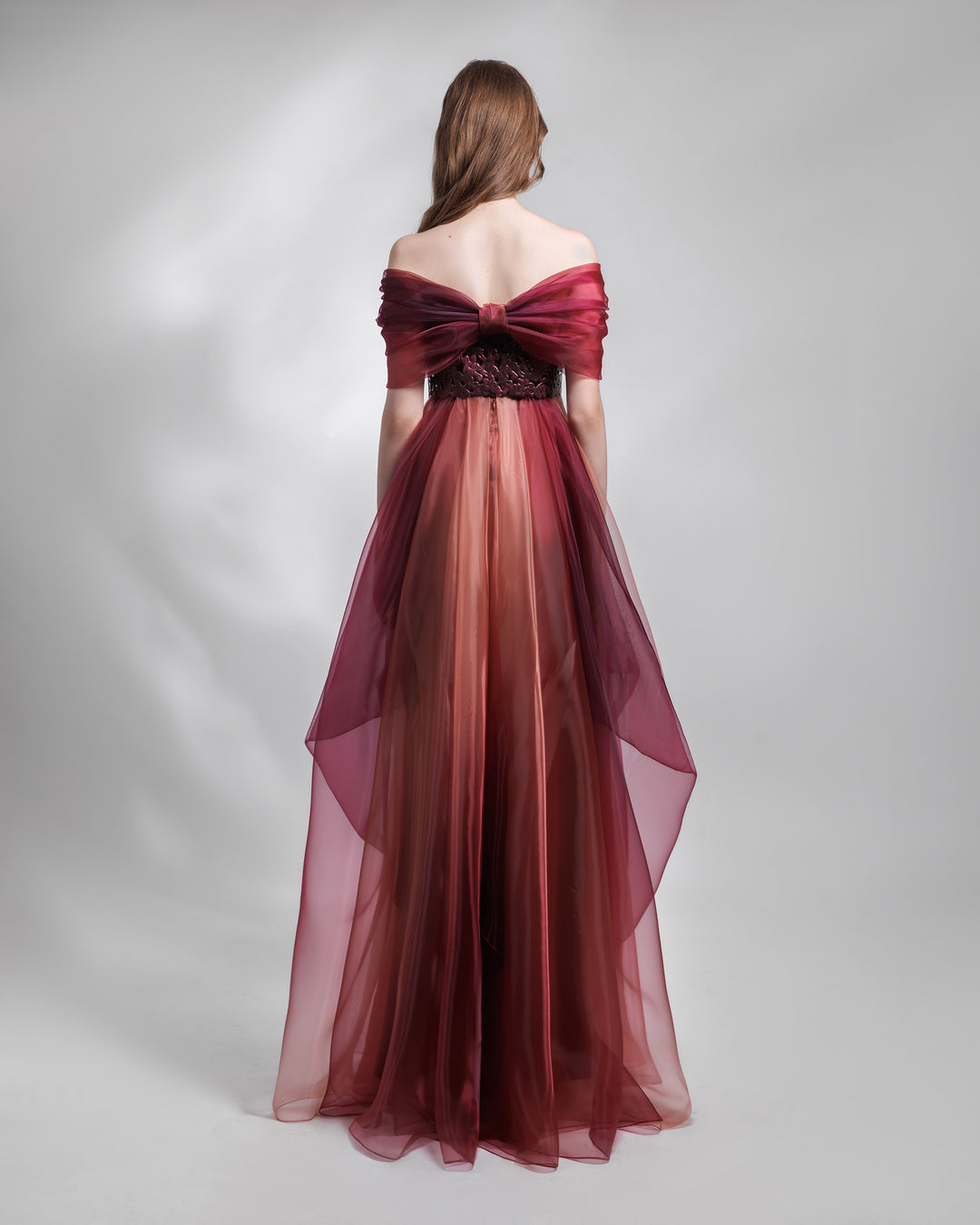 The back of a strapless organza blush aubergine dress, with laser cut intricate bodice, a bow like back design and draping details.