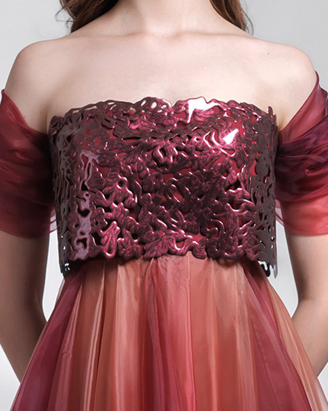 A close-up of a strapless organza blush aubergine dress, with a laser cut intricate bodice and draping details.