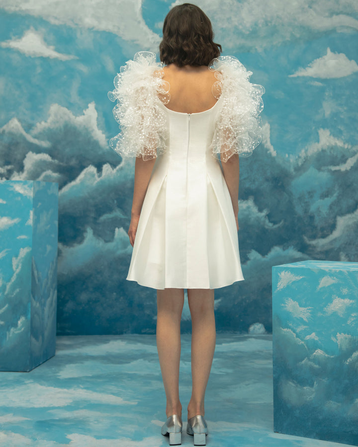 The back of a princess cut ivory short dress, comes in a jacquard fabric featuring dramatical ruffled shoulders.