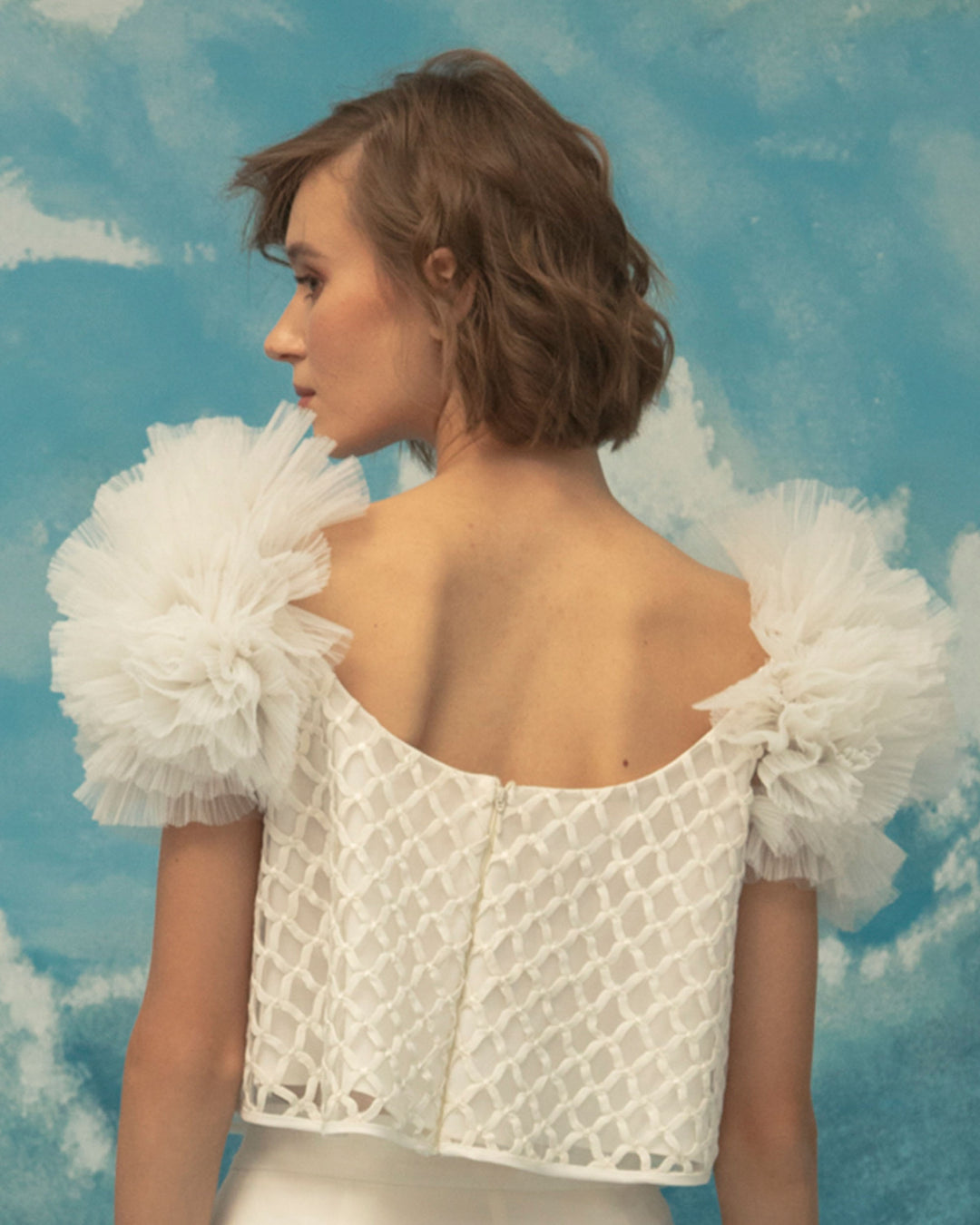 The back of an embroidered fishnet ivory top, with puffed tulle shoulders.