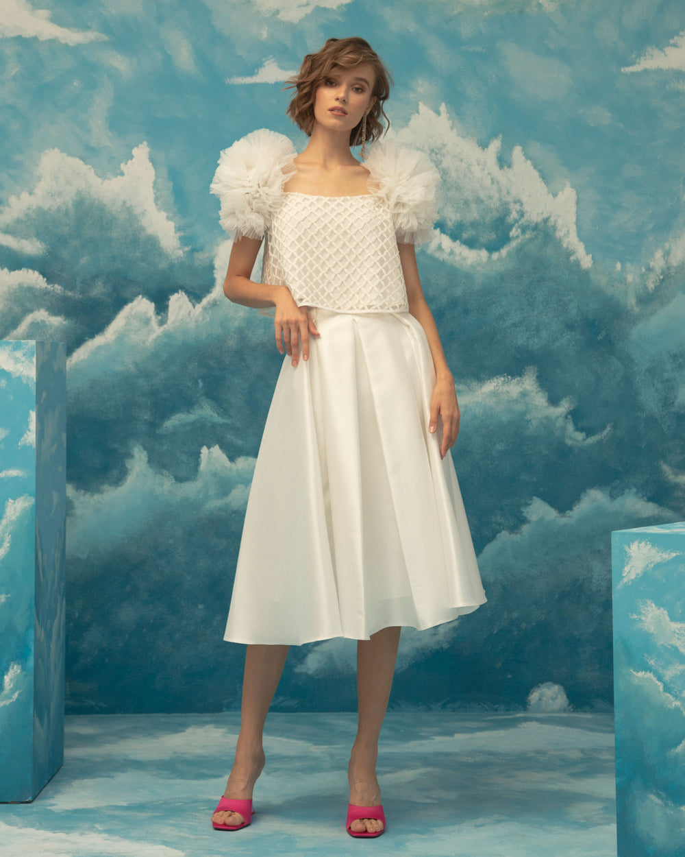 An occasion wear featuring a squared neckline, embroidered fishnet ivory top, with puffed tulle shoulders paired with an A-cut jacquard fabric midi skirt.