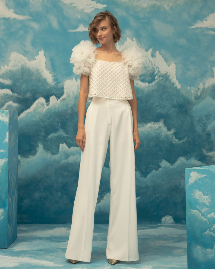 An occasion wear featuring a squared neckline, embroidered fishnet ivory top, with puffed tulle shoulders paired with a straight cut crepe pants.