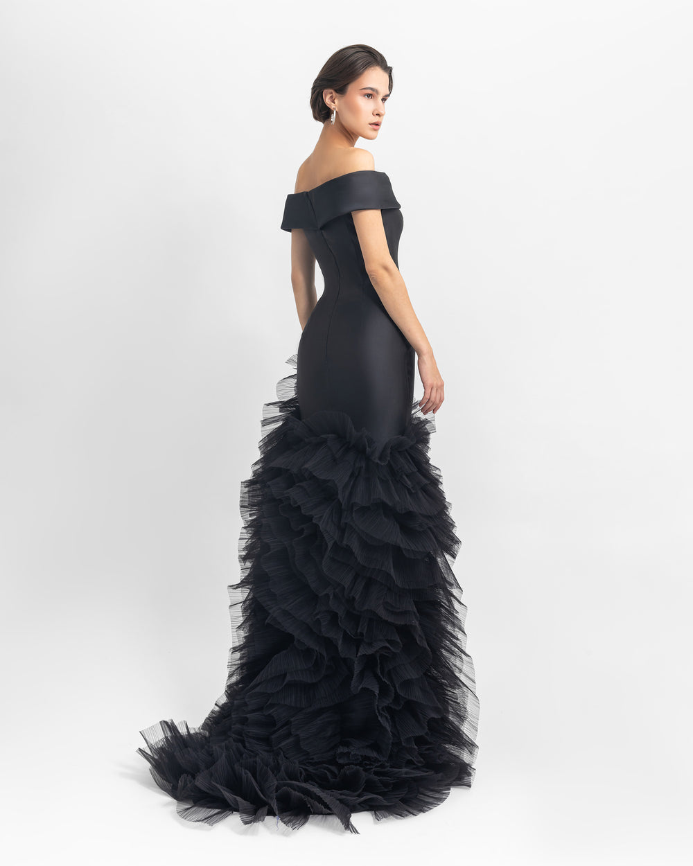 The back of an off-shoulder satin long black dress with ruffled tulle details.