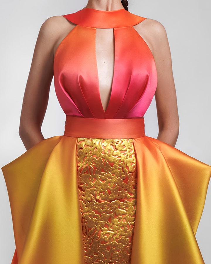 A close-up of a deep V-neckline heavy satin dress in orange, fuchsia and yellow hues, featuring an intricated laser cut skirt, with a symmetrical pleated overskirt.