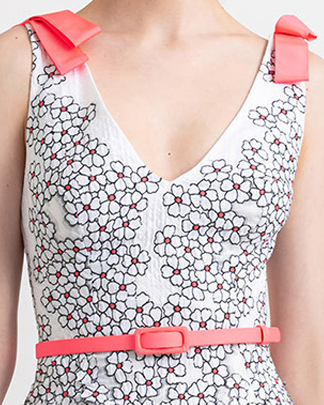 A close-up of a V-neckline top with pink bow details on the shoulders, and a detachable pink belt.