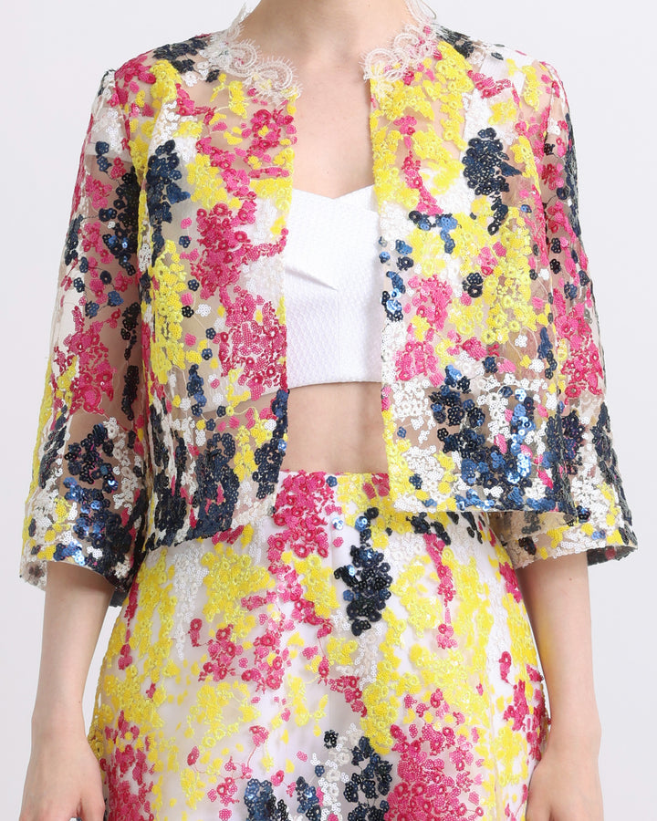 A close-up of an occasion outfit featuring a white cropped top paired with an multicolor embroidery sequins jacket and flared short sequins embroidered skirt.