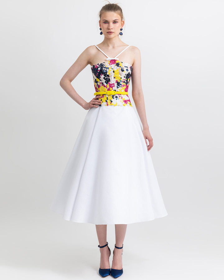 A flared white skirt paired with a multicolor corset top and a yellow belt.