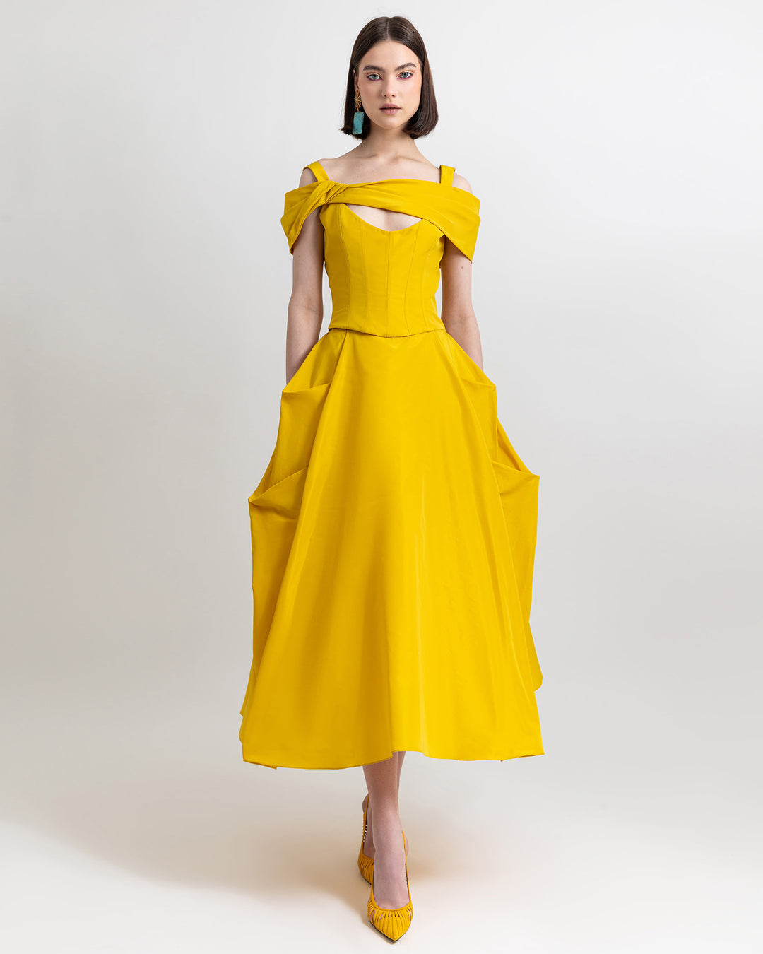 An evening wear outfit featuring an asymmetrical bow-design taffeta corset top and a wide cut taffeta skirt with draping details, all in yellow color.