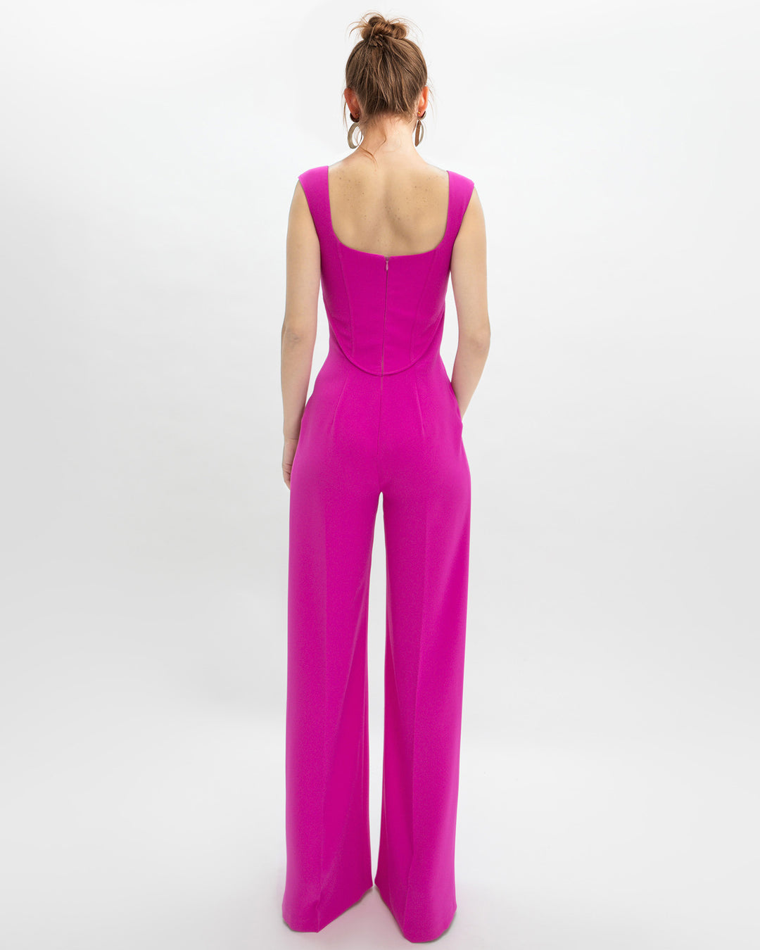 The back of a corset jumpsuit in fuchsia color.