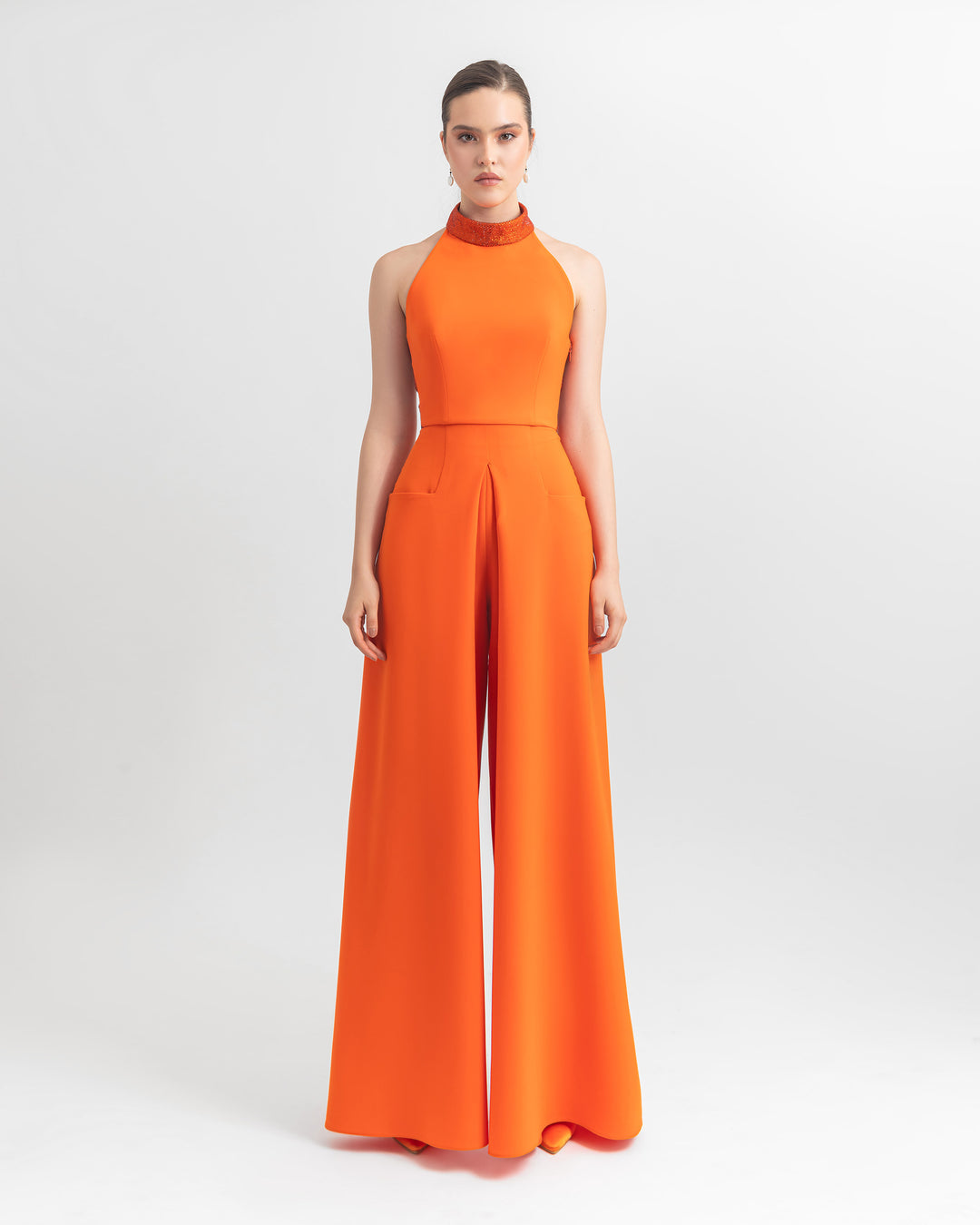 An orange halter crepe top with sequins details on the neckline paired with a wide-leg crepe pants with front pockets.