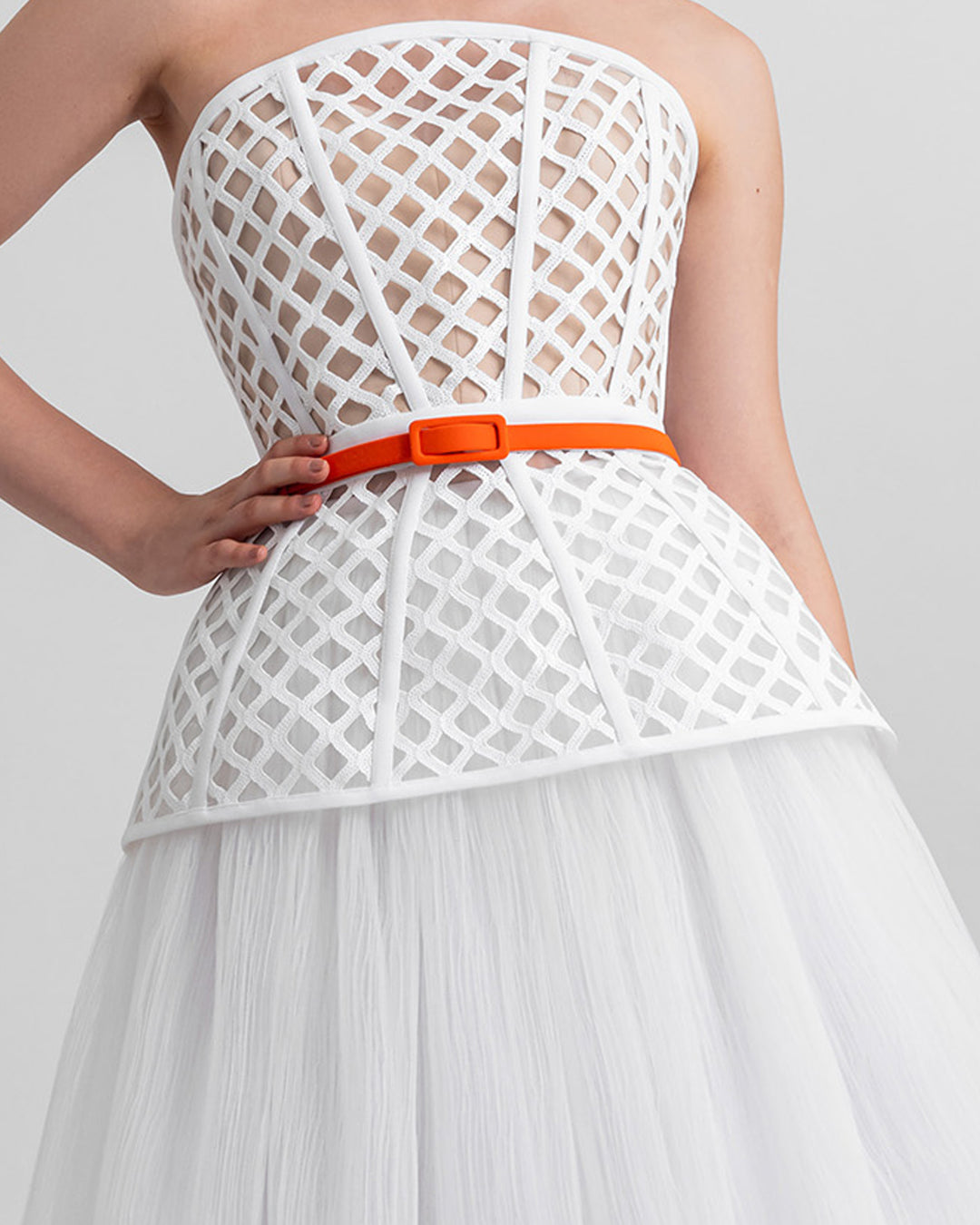 A strapless corset-like top, paired with an A-line gathered tulle skirt and a detachable orange belt.