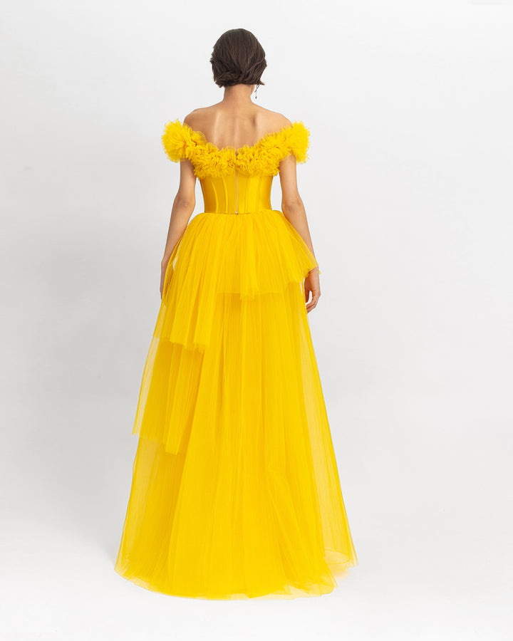 The back of a ruffled off-shoulder corset long yellow evening dress with a fully pleated tulle lower part.