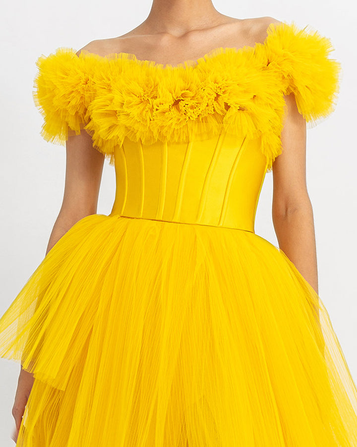 A close-up of a ruffled off-shoulder corset long yellow evening dress with a fully pleated tulle lower part.