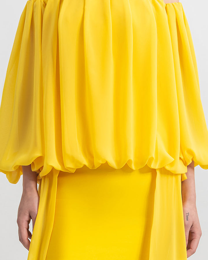 A close-up of a long sleeved loose cut chiffon yellow evening dress.