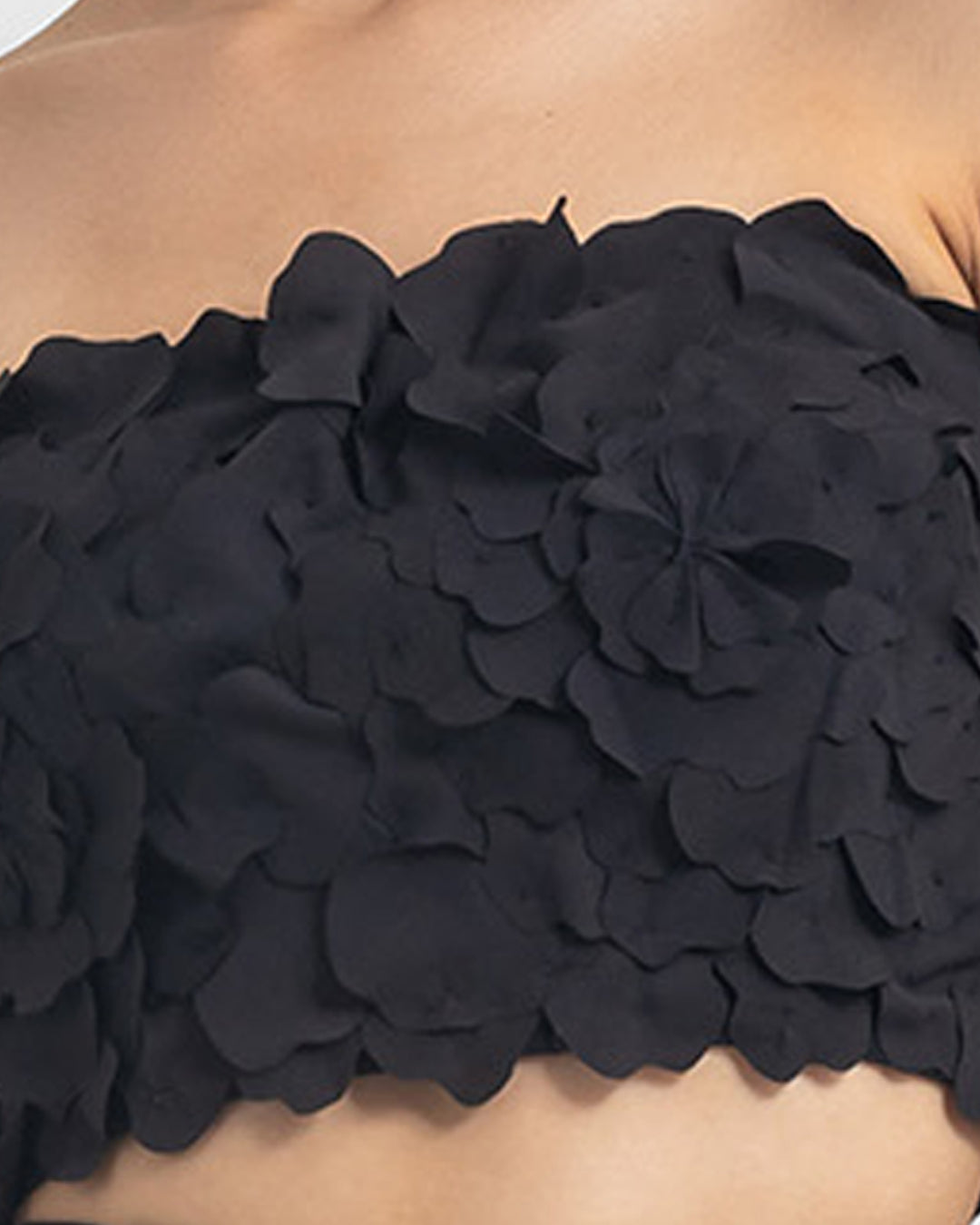 A close-up of a strapless black cropped-top with laser cut details.