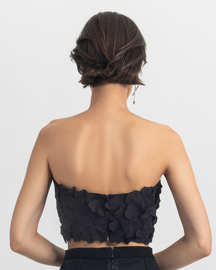 The back of a strapless black cropped-top with laser cut details.