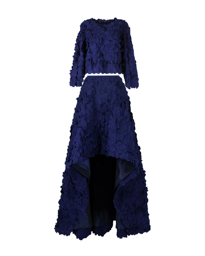 An evening wear featuring a straight-cut laser-cut navy blue top with open-sleeve details, paired with a wide asymmetrical hemline laser-cut navy blue skirt and a detachable belt.