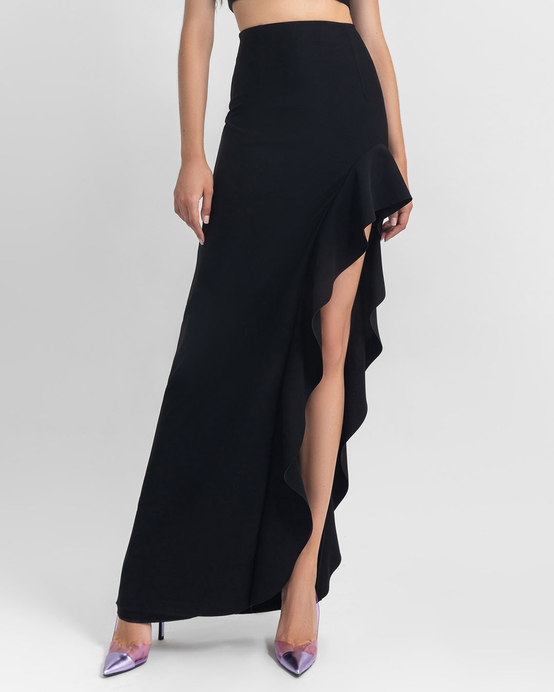 An asymmetrical black crepe skirt with ruffled details and a slit on the side.