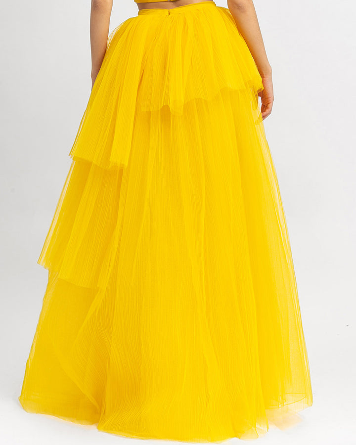 The back of a fully pleated wide tulle yellow skirt.