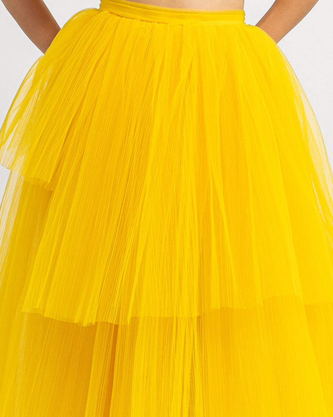 A close-up of a fully pleated wide tulle yellow skirt.