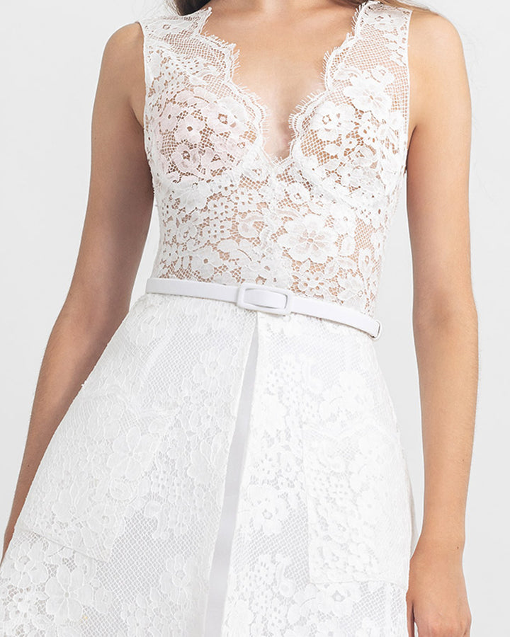 A close-up of a deep v-neckline white lace top, paired with a cage-like lace skirt and a detachable white belt.