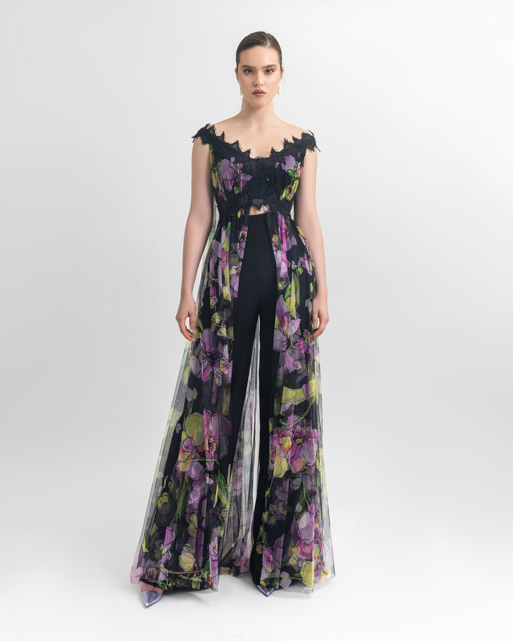 An off-shoulder multicolored long floral tulle top with an open slit at the front, paired with straight-cut crepe black pants.