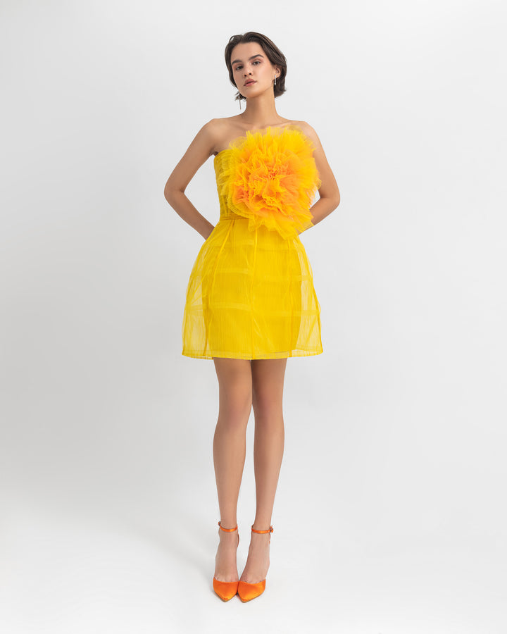 A yellow evening wear set featuring a flower draped tulle corset, paired with a cage design mini skirt.