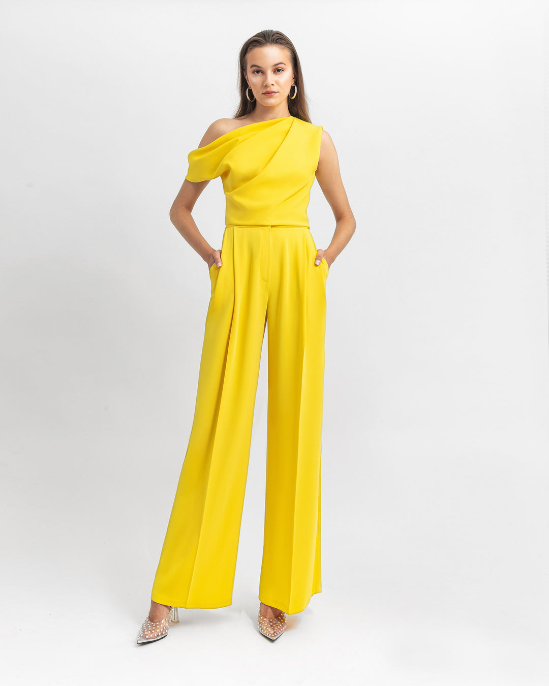 An asymmetrical cut crepe yellow top with draping details paired with a straight cut crepe pants.