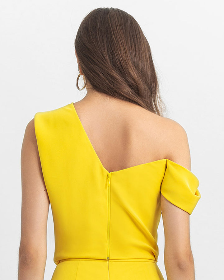 The back of an asymmetrical cut crepe yellow top with draping details.