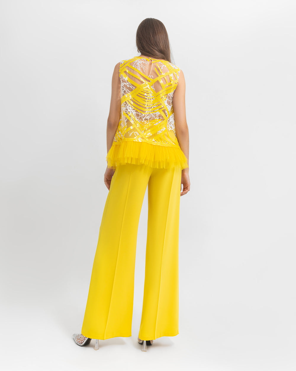 The back of an occasion wear set featuring a straight cut sequin top with tulle details paired with a yellow crepe pants.