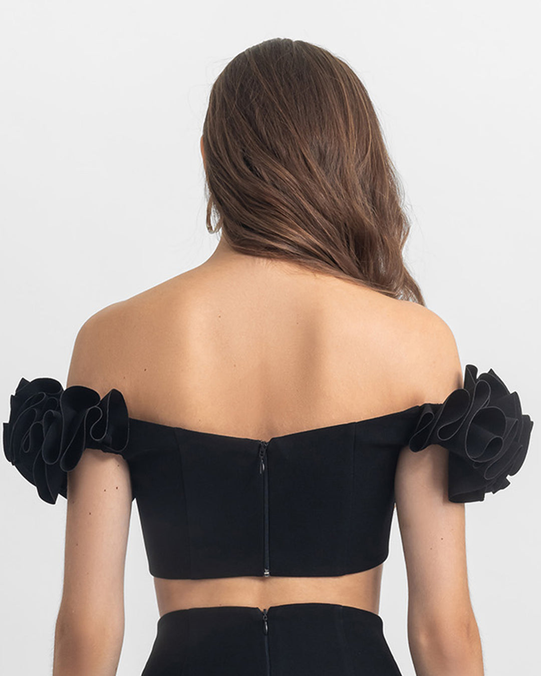 The back of an off-shoulders ruffled crepe black crop top.