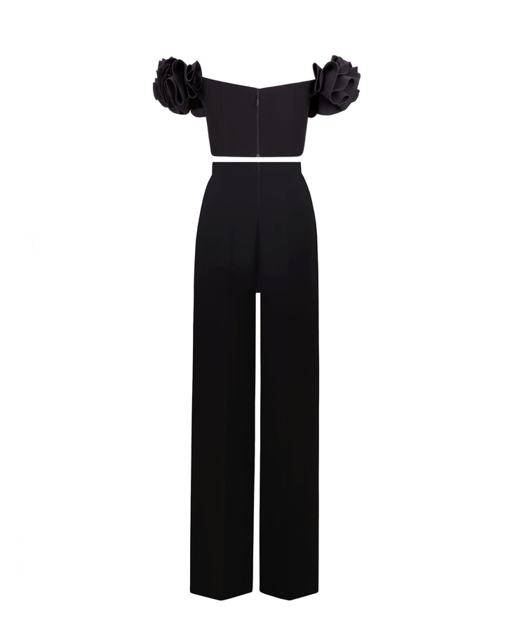 The back of a black evening wear set featuring an off-shoulder ruffled crepe top, paired with straight cut crepe pants and a detachable belt.