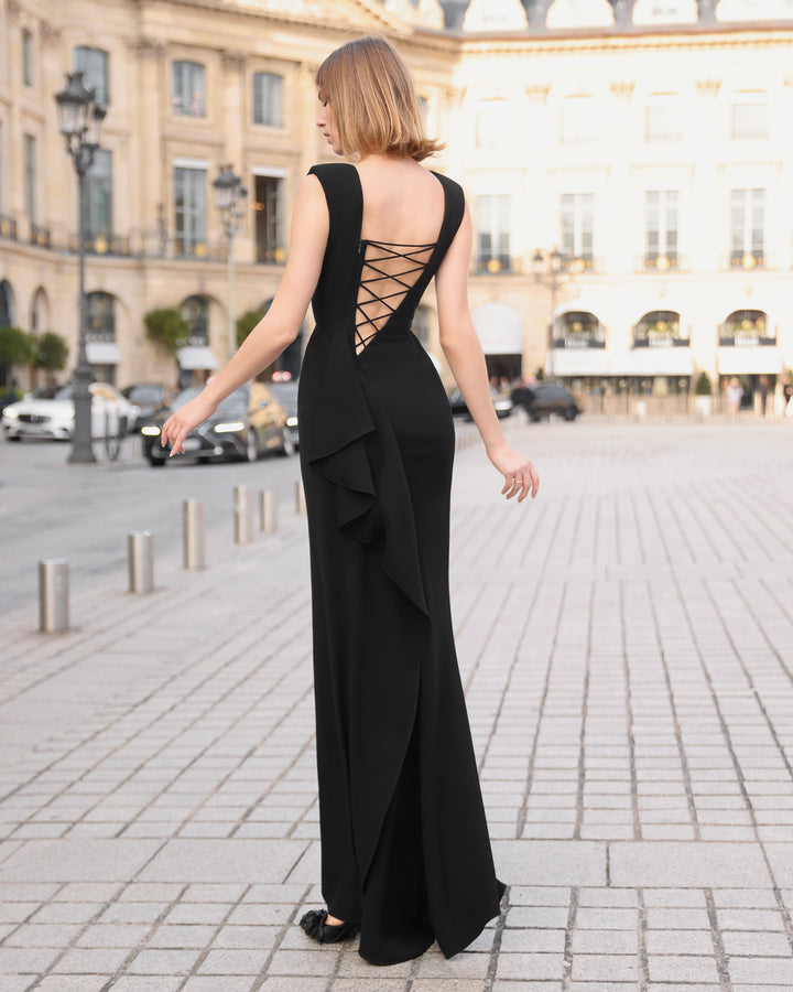 A slim cut black evening dress with a lace-up backless design and ruffles details on a side slit.