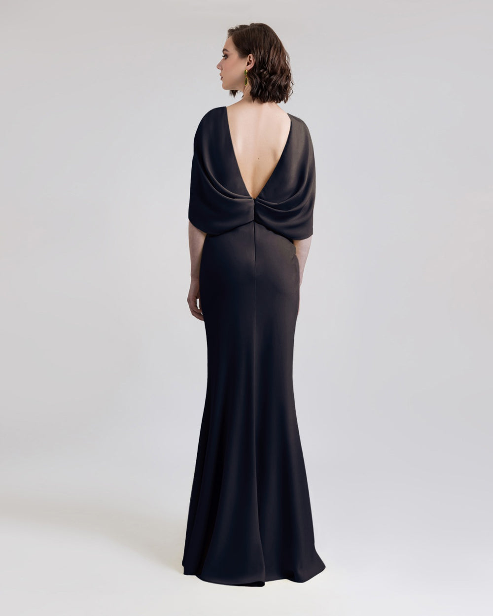 A Deep V-shaped open back black evening dress featuring cape-like sleeves.